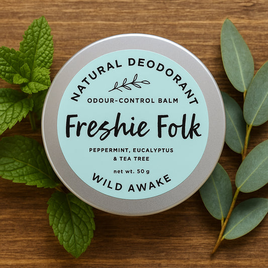 Freshie Folk natural deodorant balm on a wooden surface with mint and eucalyptus  leaves